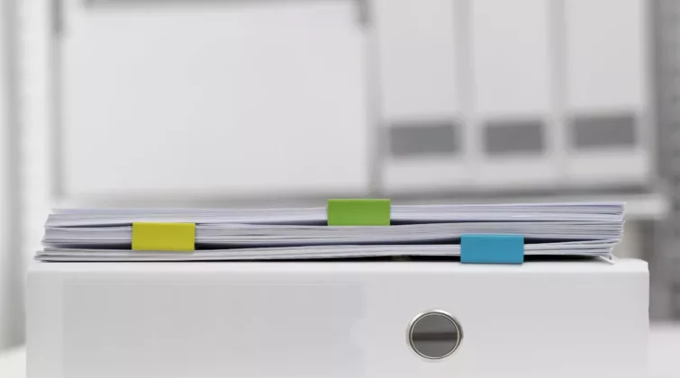 Des dossiers empilés sur un classeur rempli d'actes administratifs