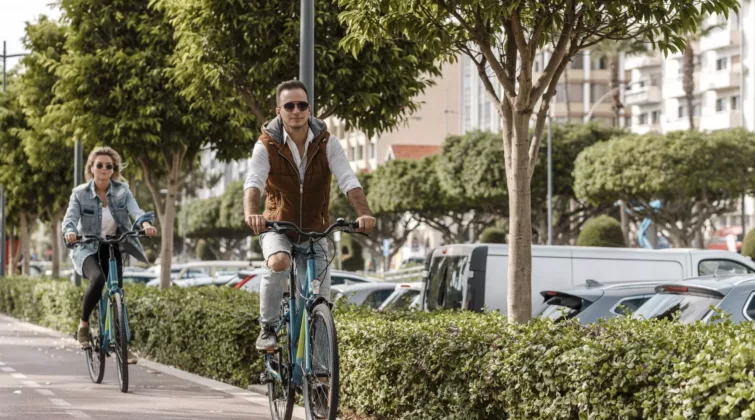 Un homme et une femme pédalent sur un piste cyclable, le long d'une rue animée