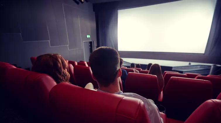 Vue d'un écran de cinéma depuis le haut de la salle, derrière les sièges