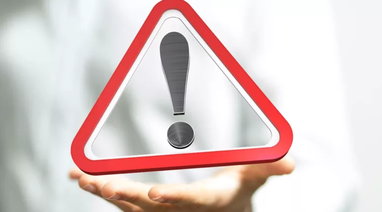 Une main tenant un panneau triangulaire avertissant d'un danger ou d'un risque