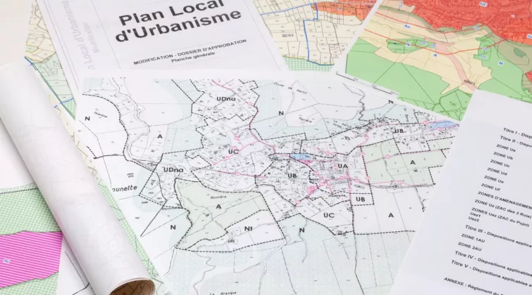 Des documents relatifs au PLU (carte, liste...) étalés sur un bureau