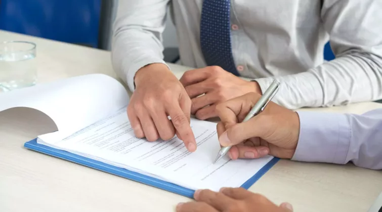 Une personne indique à une autre où signer un document