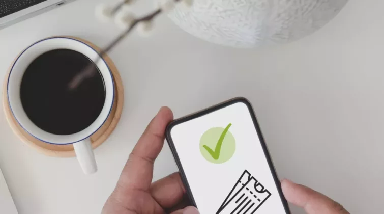 Image d'un smartphone tenu par des mains d'homme ; l'écran montre une validation après l'achet de billets