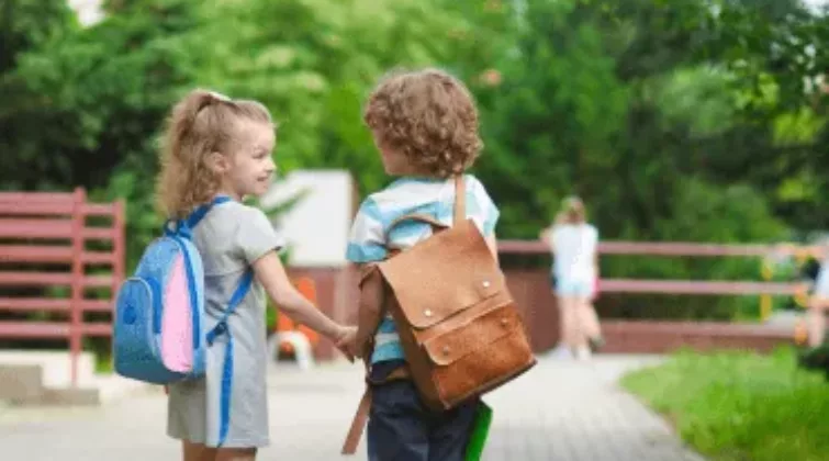 deux jeunes enfants portant des cartables et se tenant la main