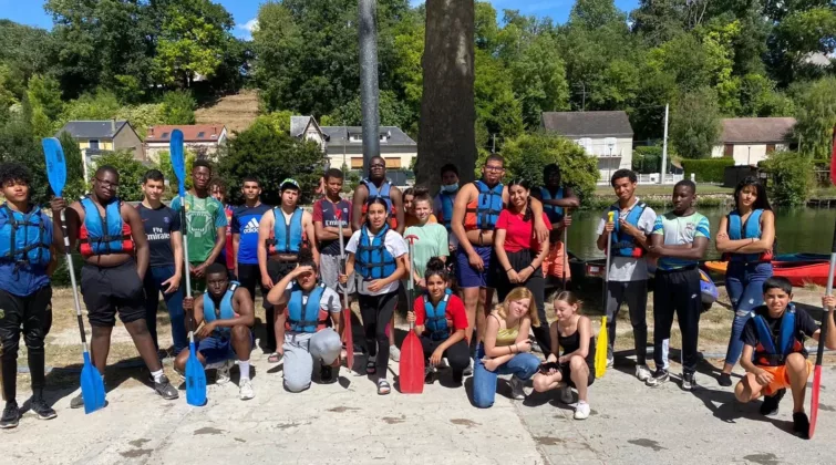 Un groupe d'adolescents sur les bords du Loing, portant de gilets de sauvetage et tenant des rames, en vue d'une activité type kayak