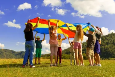 groupe d'enfant debout sur un champ d'herbe verte en plein journée de soleil (Le centre de loisirs)