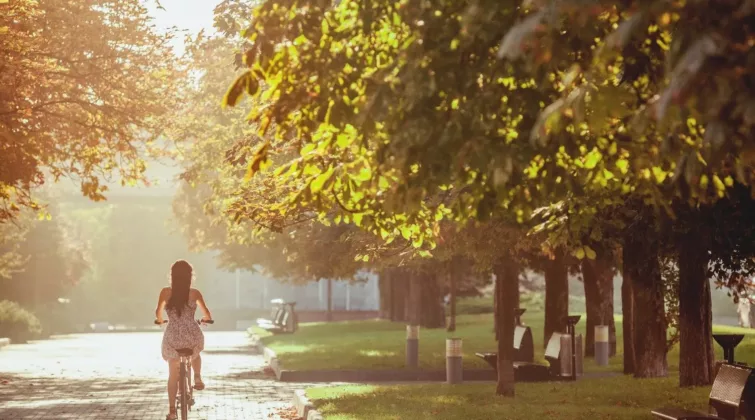 femme à vélo se promenant dans la ville entourée d'espaces verts