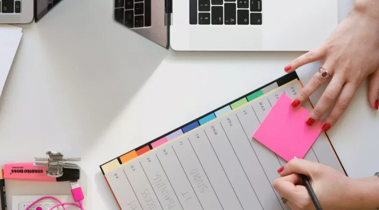 main qui écrit sur un agenda et un post it