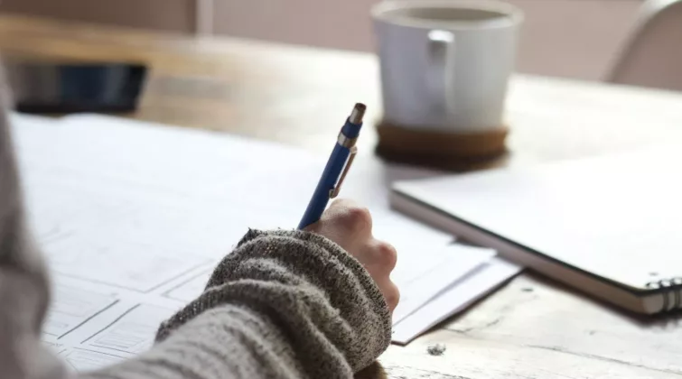personne écrivant sur une feuille