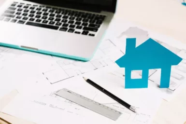 ordinateur et maison en papier sur des plans de travaux