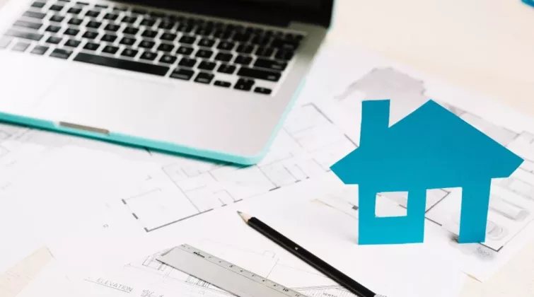 ordinateur et maison en papier sur des plans de travaux
