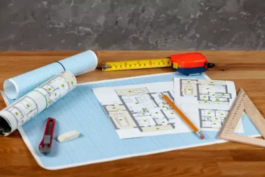 Des plans de construction et des outils sont posés sur une table