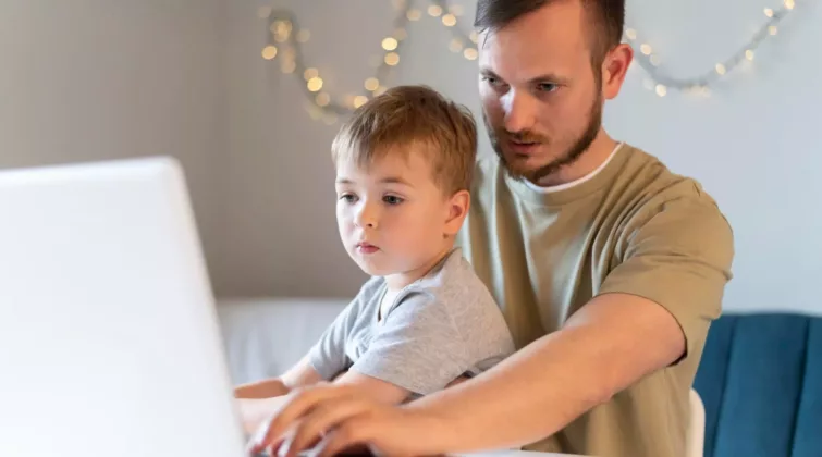 un père consulte une page internet avec son petit garçon sur les genoux - crédit photo : freepik