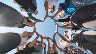 Des personnes sont en rond et forment un cœur avec leurs mains