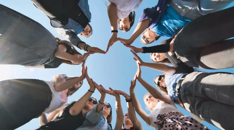 Des personnes sont en rond et forment un cœur avec leurs mains