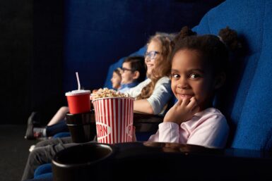 des enfants souriants vus de profil assis dans une salle de spectacle. crédit photo : freepik