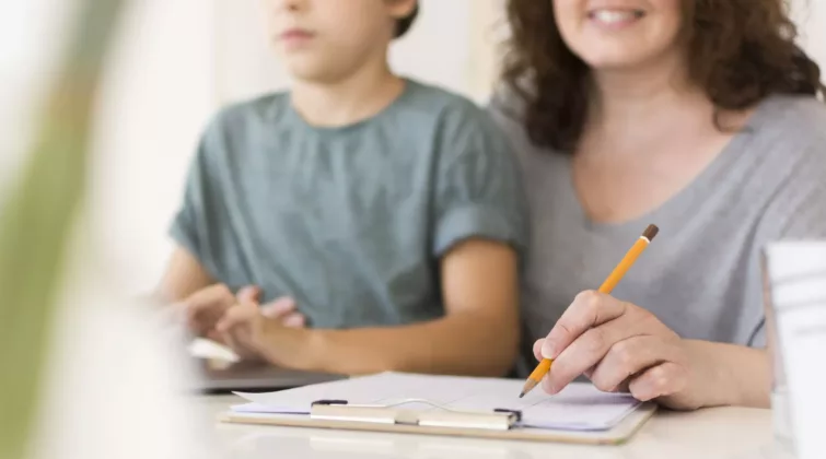 un enfant et une adulte prennent des notes tout en consultant un site internet - crédit photo : freepik