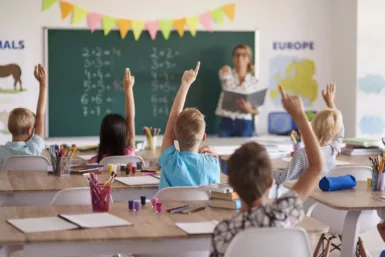 Classe d'enfant qui lèves la main dans une école