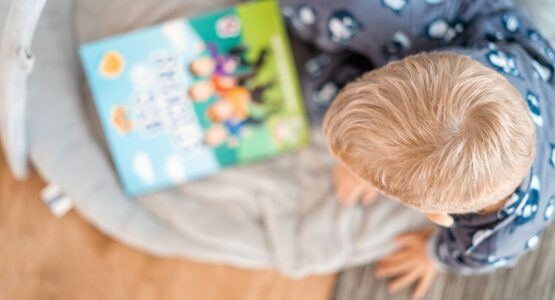 a little boy reading a book on a bed
