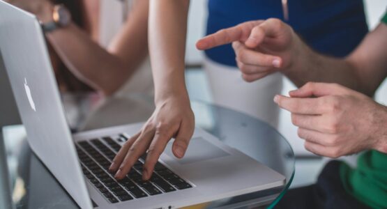person touching and pointing MacBook Pro